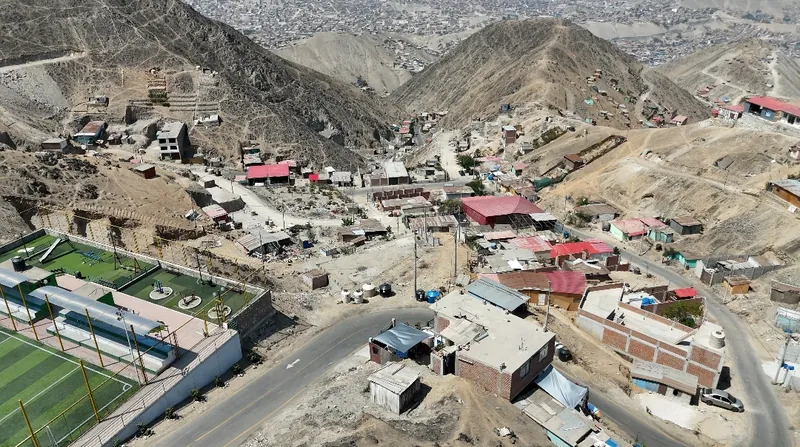Vista aérea real de la asociación con dron: el polideportivo, la pista asfaltada y las manzanas entre los cerros